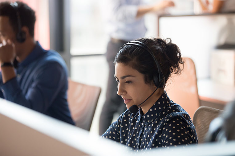 Woman sitting at computer with headset working at a contact center