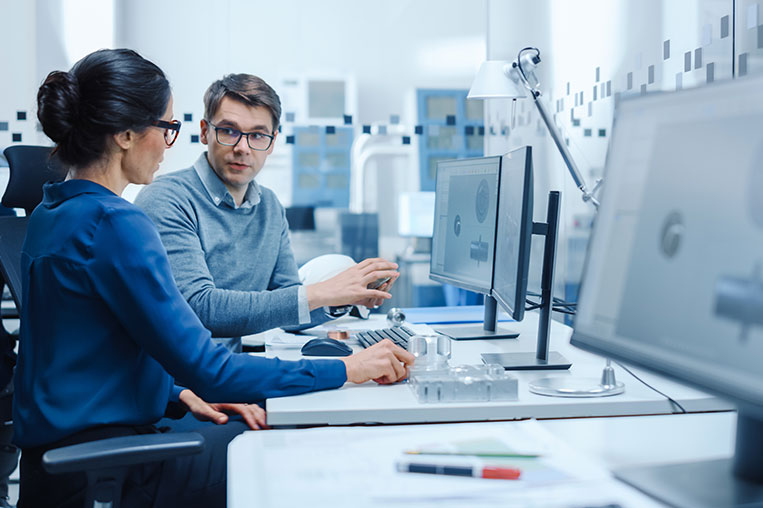 Man and woman sitting at computer reviewing Cloud Managed Services