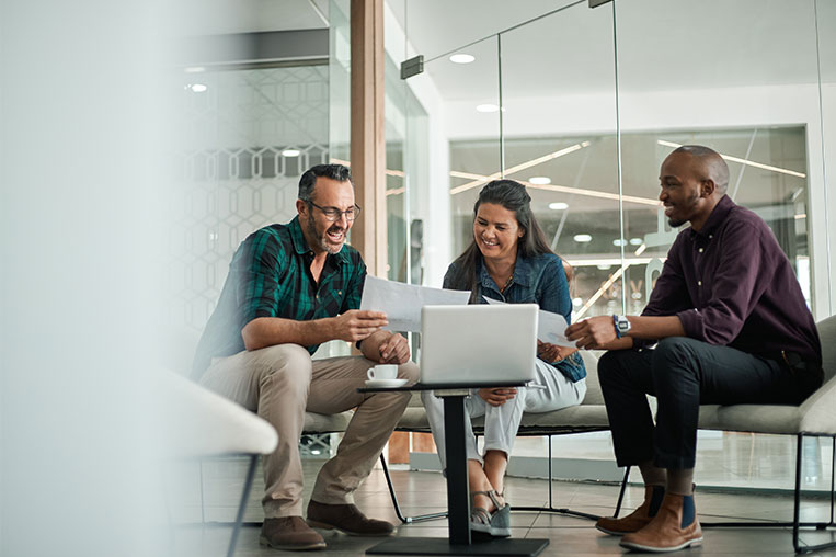 Three team members sitting casually in front of a computer discussing CRM strategy