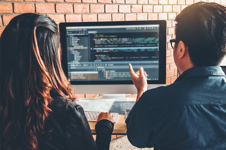 Man and woman working at a computer reviewing cybersecurity code