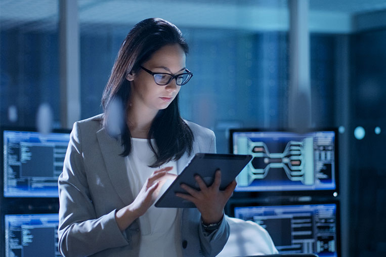 Woman examining tablet with cybersecurity coding on display int he background