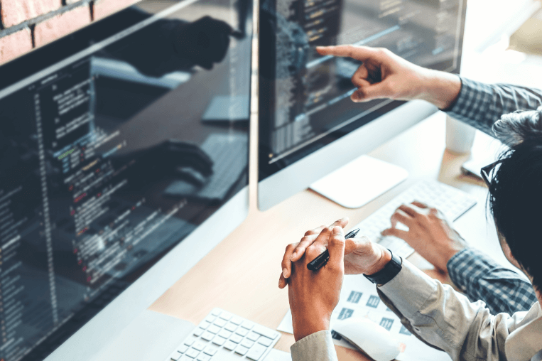 Two coworkers sitting at desktop reviewing code